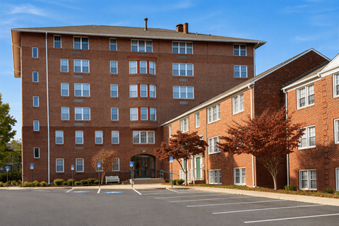A large red brick building with a parking lot in front.