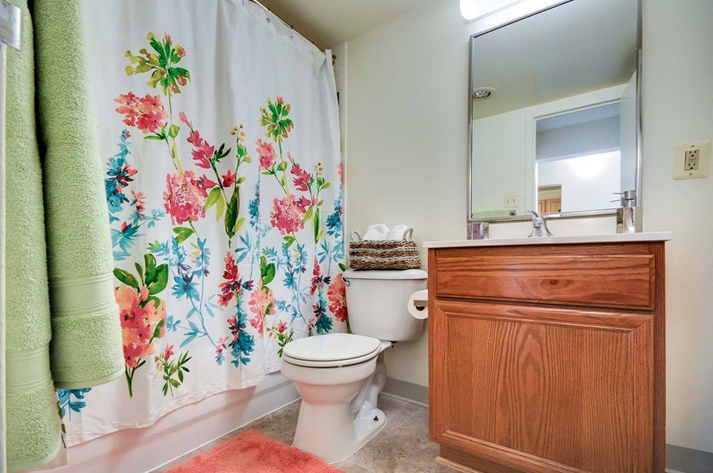 spacious, full bathroom featuring large tub/shower combo with a floral shower curtain