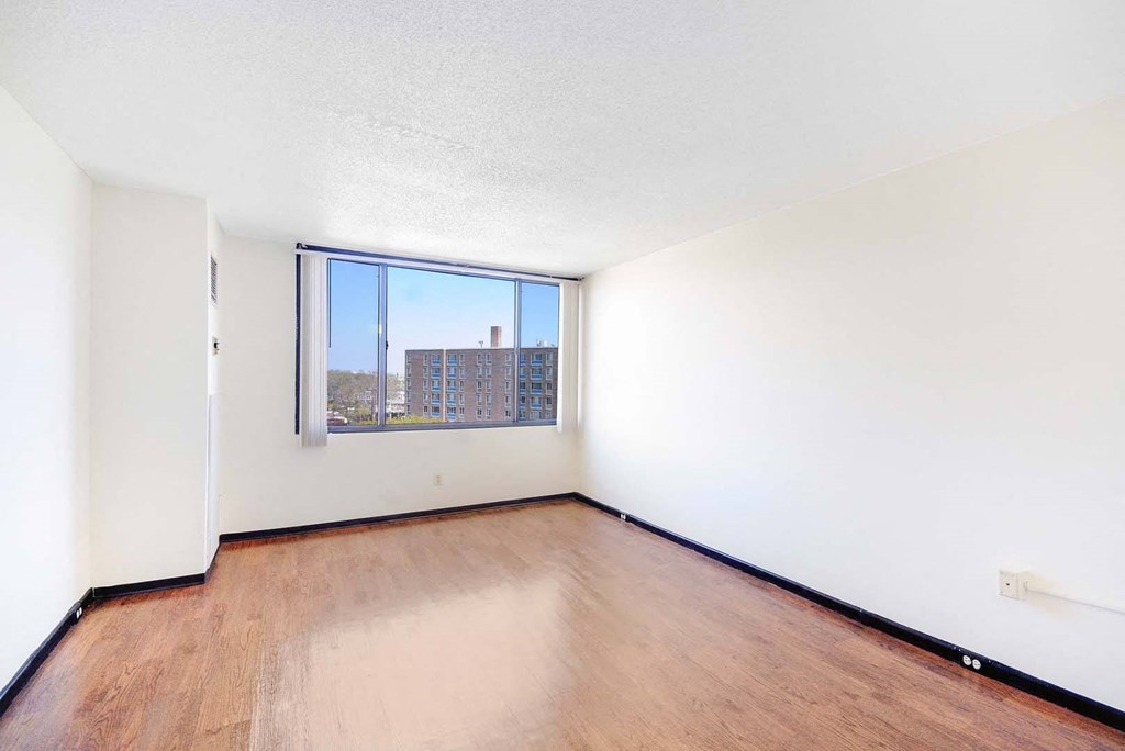 Spacious bedroom with a large picture window and hardwood floors