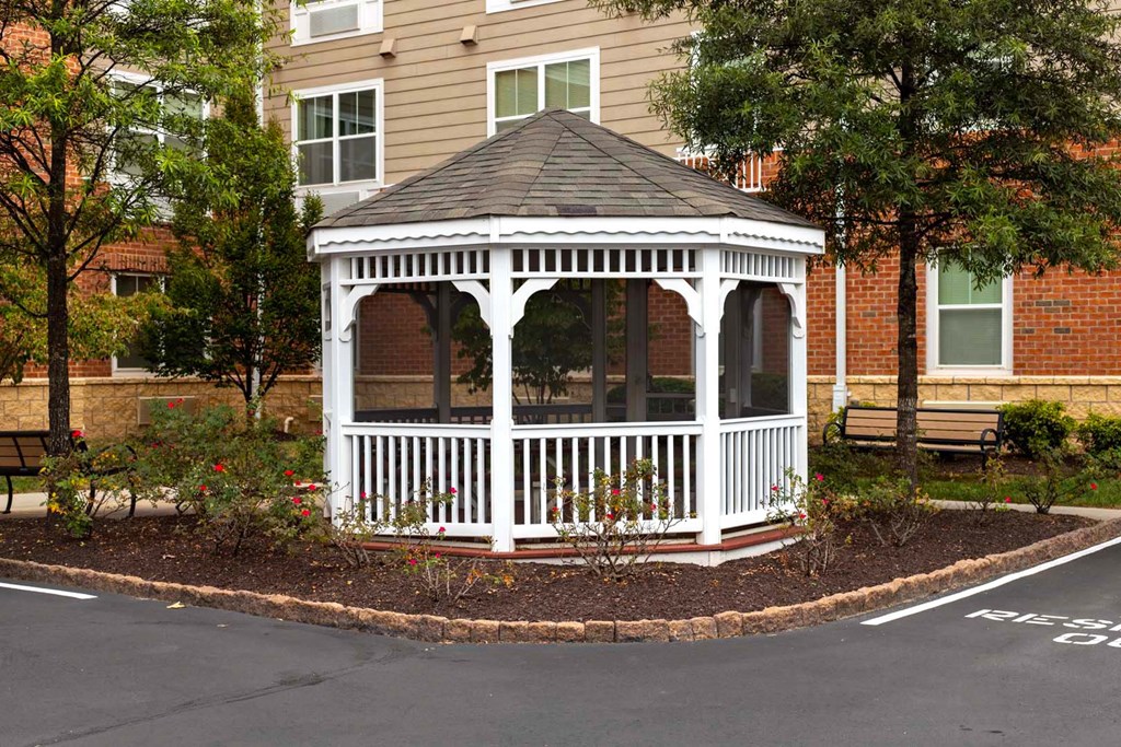 a white gazebo in a garden area in front of a house