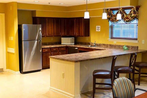 a kitchen with a bar and a stainless steel refrigerator