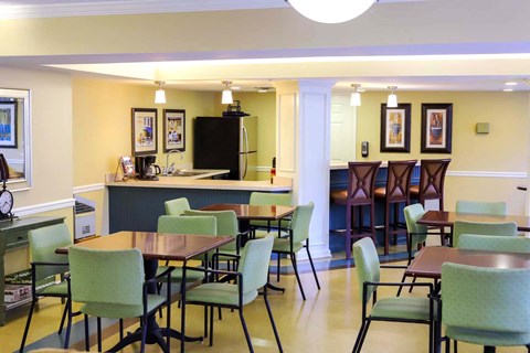 a dining room with tables and chairs and a kitchen with a counter