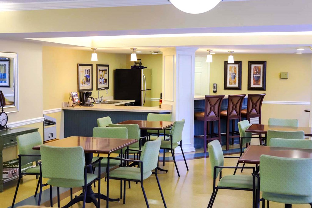 a dining room with tables and chairs and a kitchen with a counter