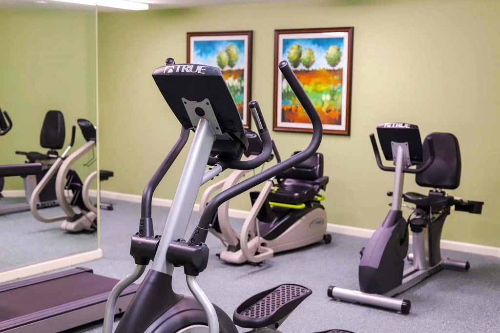 A fitness center with exercise equipment and a green wall.