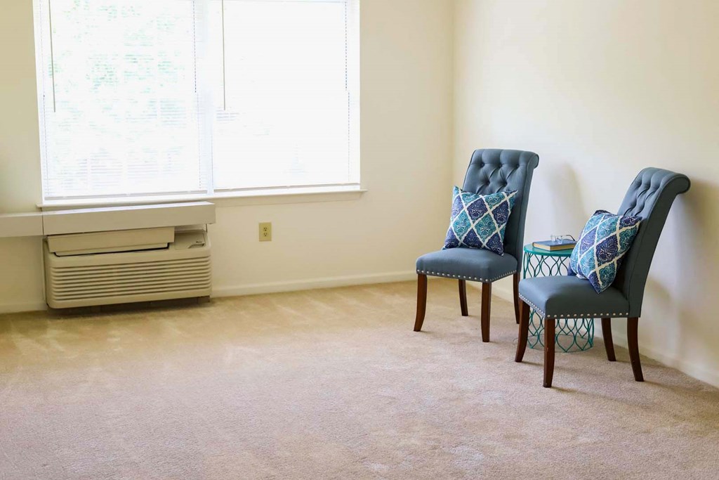 a living room with two blue chairs and an air conditioner