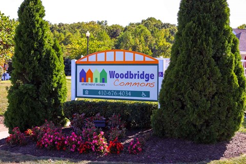 the sign for woodbridge commons in front of trees and flowers
