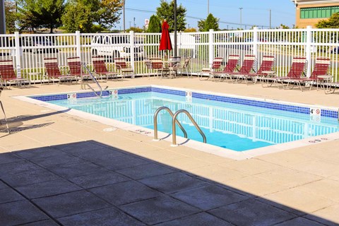 a swimming pool with chairs around it next to a fence