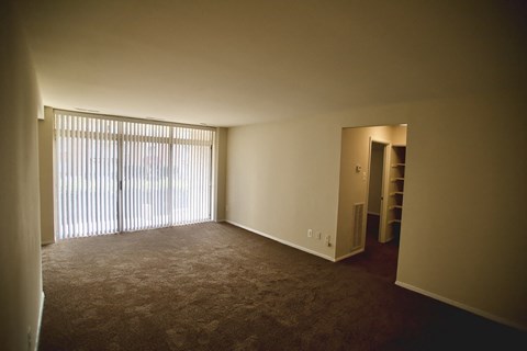 an empty living room with blinds and a window