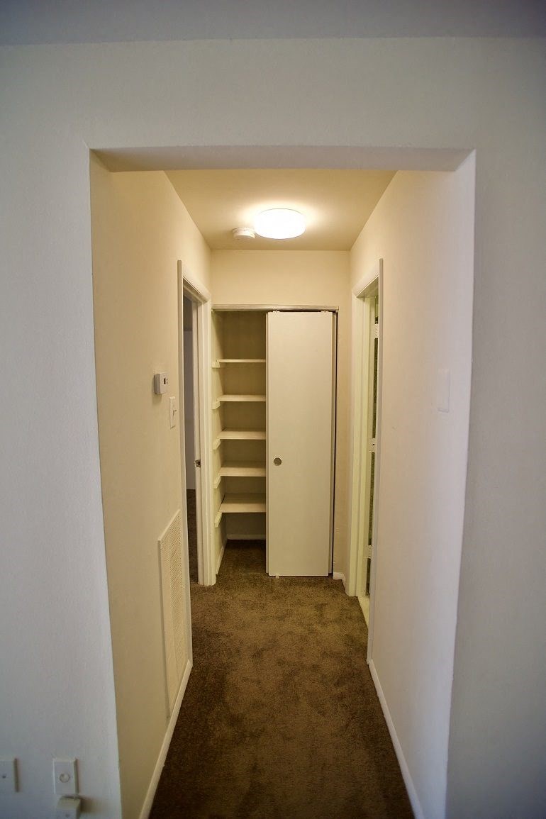 a hallway with a closet and shelves in a house