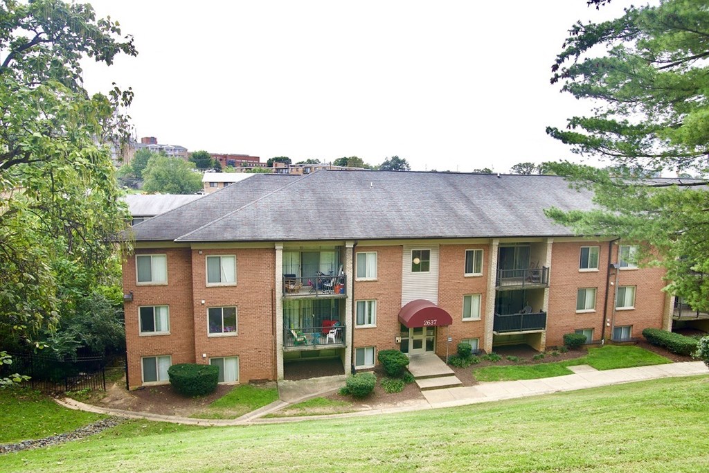 a brick apartment building with a yard and trees