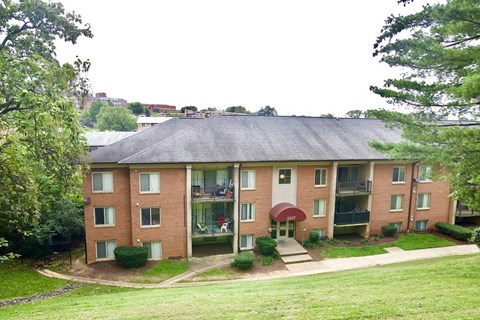 a brick apartment building with a yard and trees