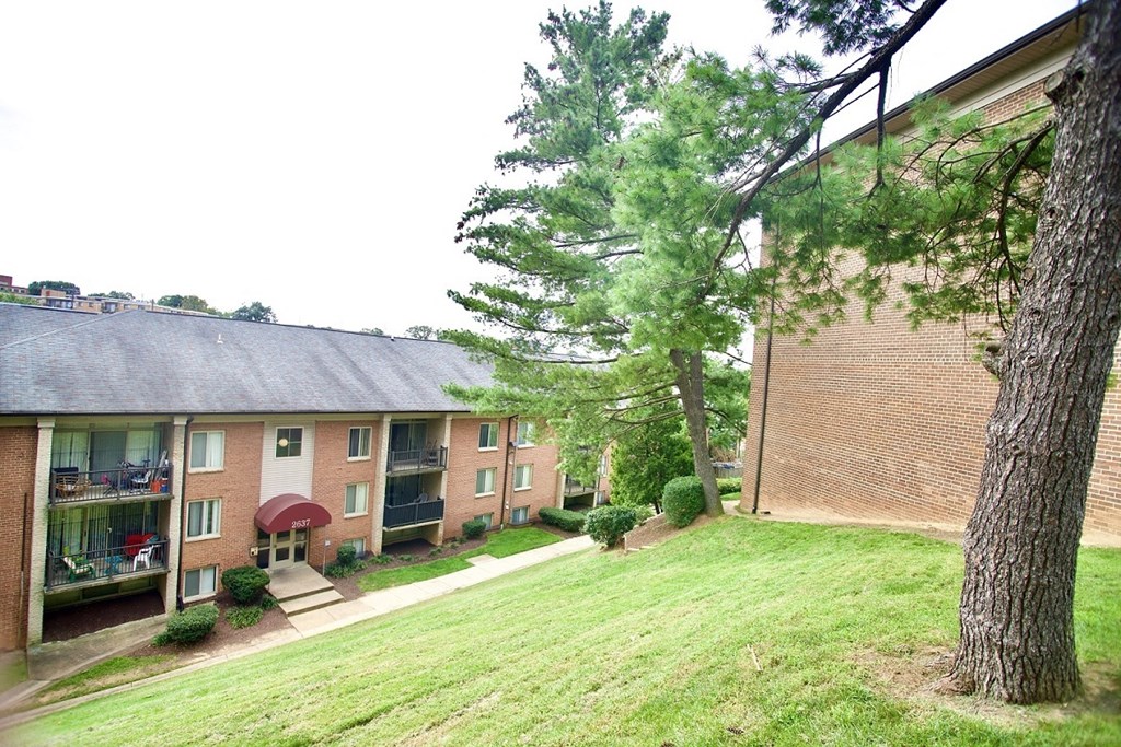 the outlook of a brick apartment building with grass and trees