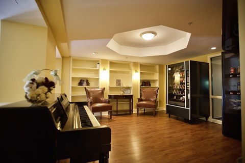 a large living room with a piano and chairs