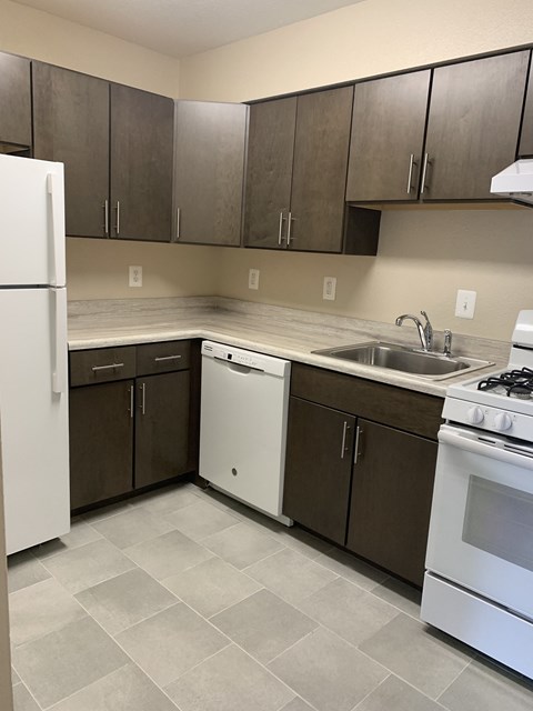 an empty kitchen with a stove refrigerator and sink
