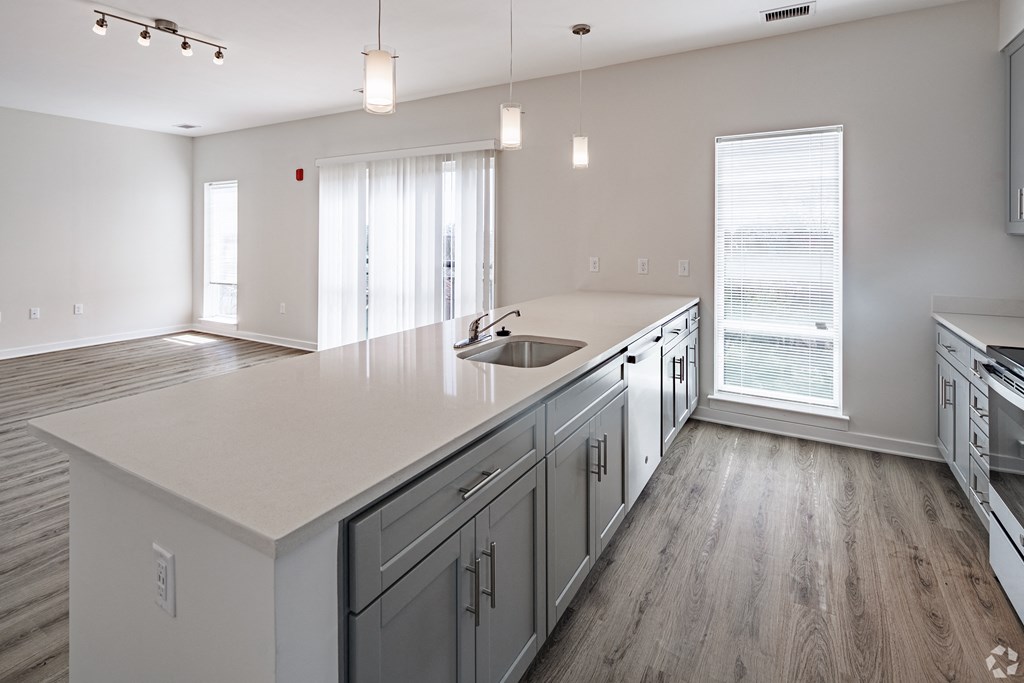 an open kitchen and living room with white countertops and a large white counter top
