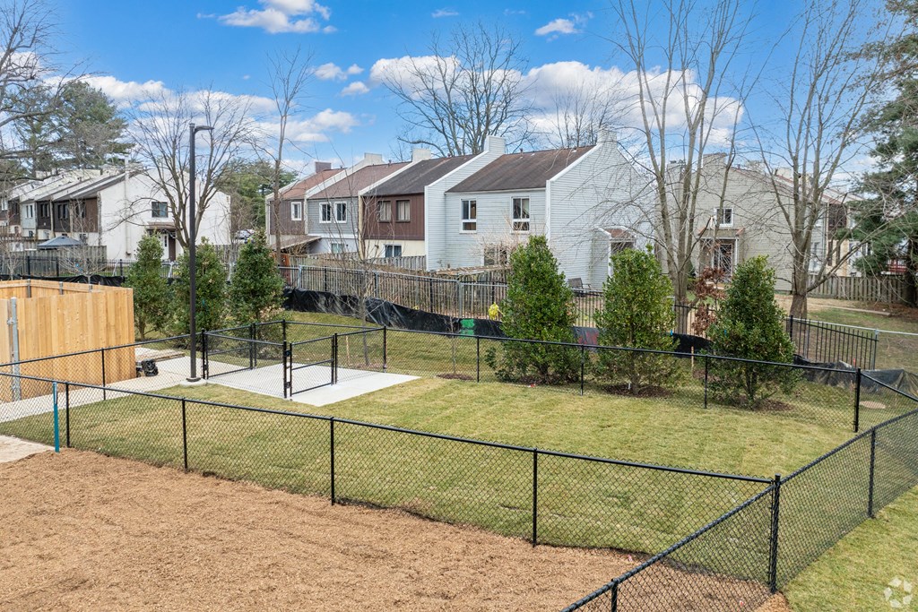 the view of a fenced in dog park with houses in the background