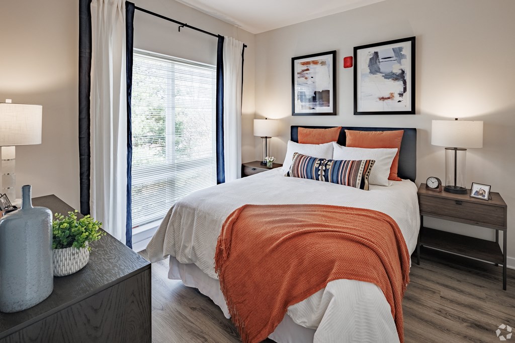 a bedroom with an orange and white bed and a window