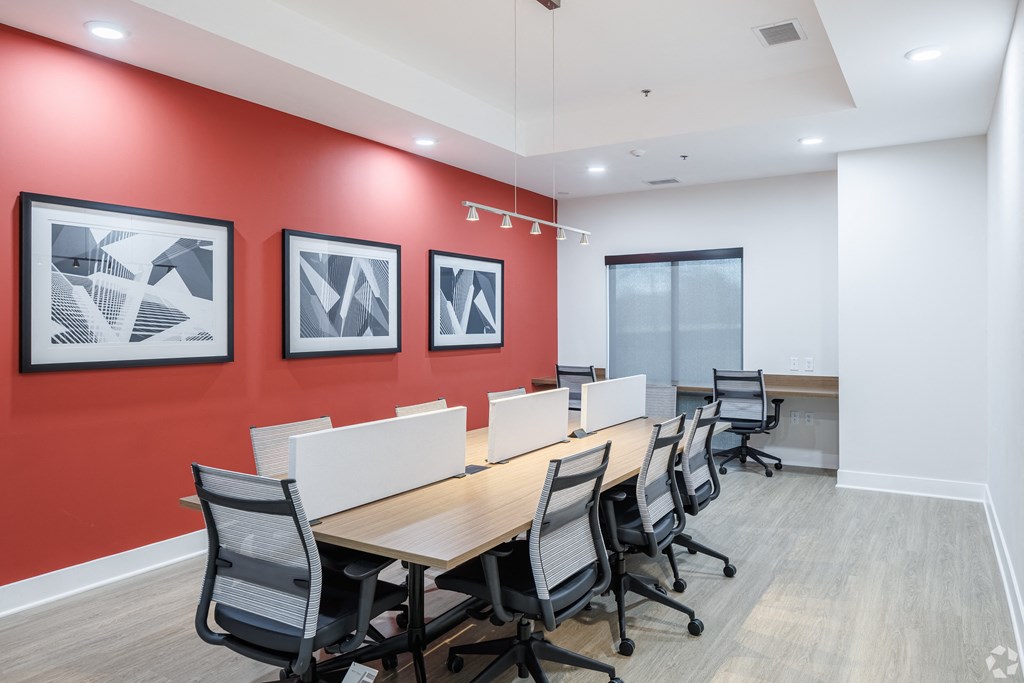 a conference room with a long wooden table and chairs and a red accent wall