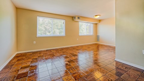 an empty living room with wooden floors and two windows
