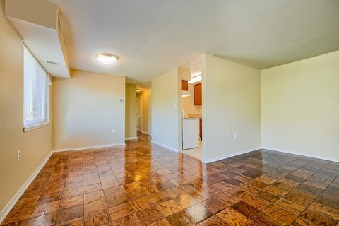 an empty living room with wood flooring and a kitchen