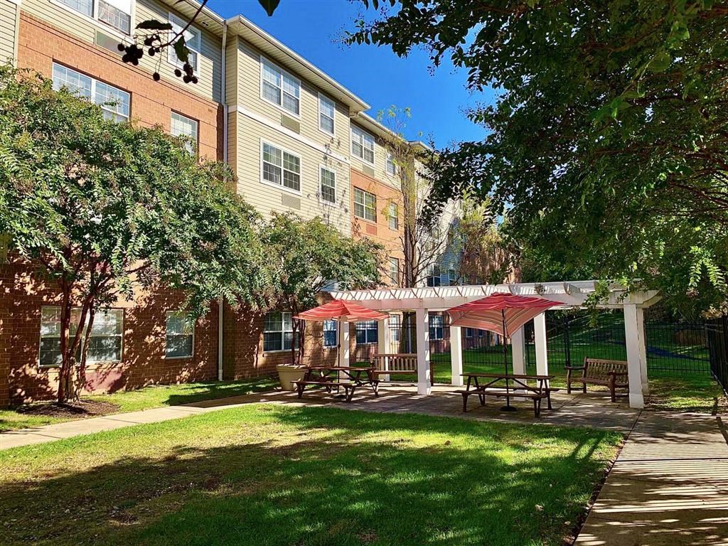 a patio with tables and umbrellas in front of an apartment building
