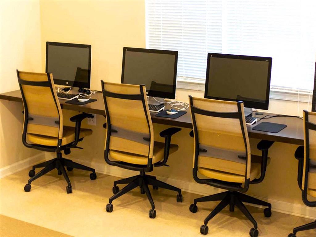 a desk with computers and chairs in an office
