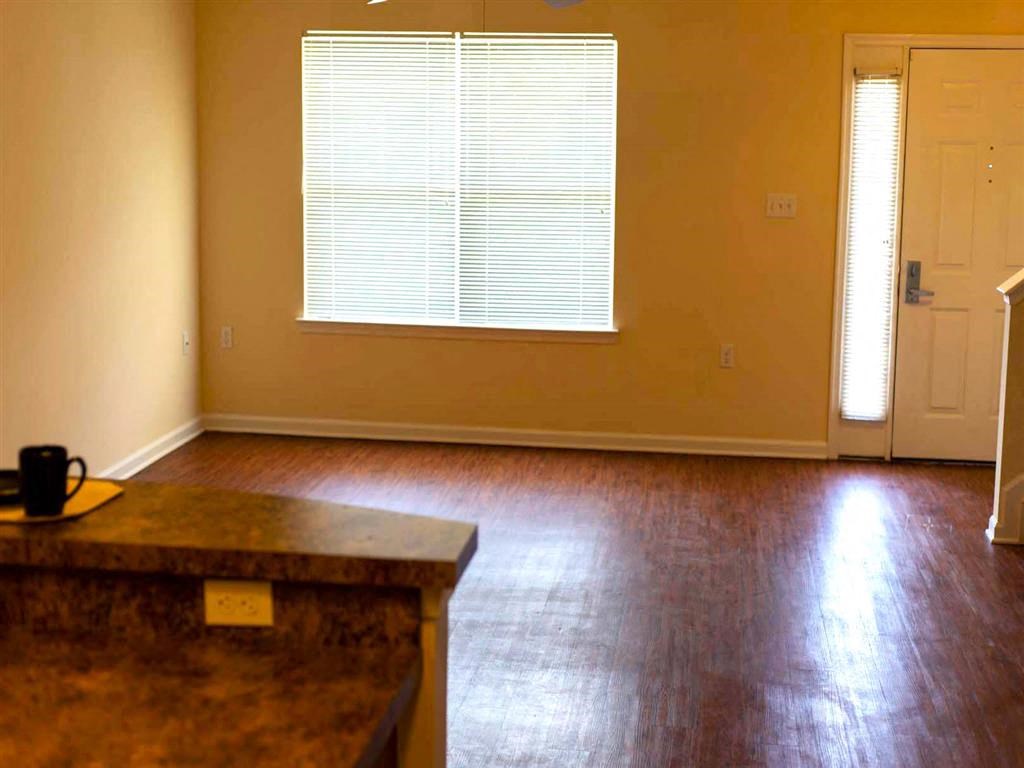 an empty living room with wood floors and a window