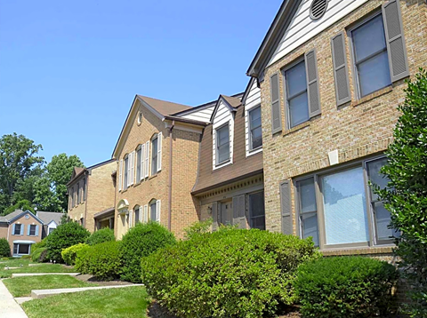a row of brick apartment buildings with grass and bushes