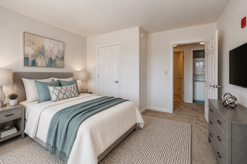A bedroom with a bed, nightstand, and a painting on the wall.