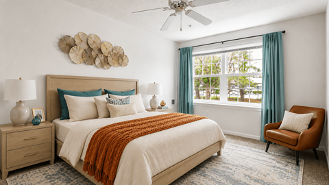 A bedroom with a large bed, a ceiling fan, and a window with blue curtains.