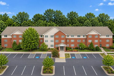 A large red brick building with a parking lot in front.
