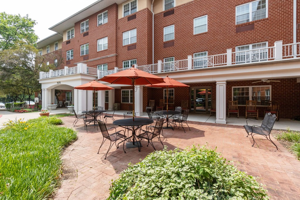 a patio with tables and umbrellas in front of a brick building