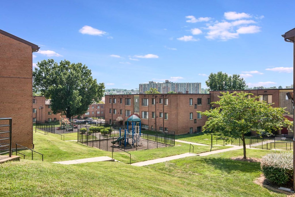 Exterior view of Meadowbrook Run Apartments, an Enterprise community in Congress Heights, Washington, D.C., surrounded by mature trees and green space, showcasing a peaceful park-like setting.