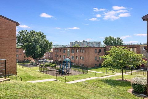 Exterior view of Meadowbrook Run Apartments, an Enterprise community in Congress Heights, Washington, D.C., surrounded by mature trees and green space, showcasing a peaceful park-like setting.
