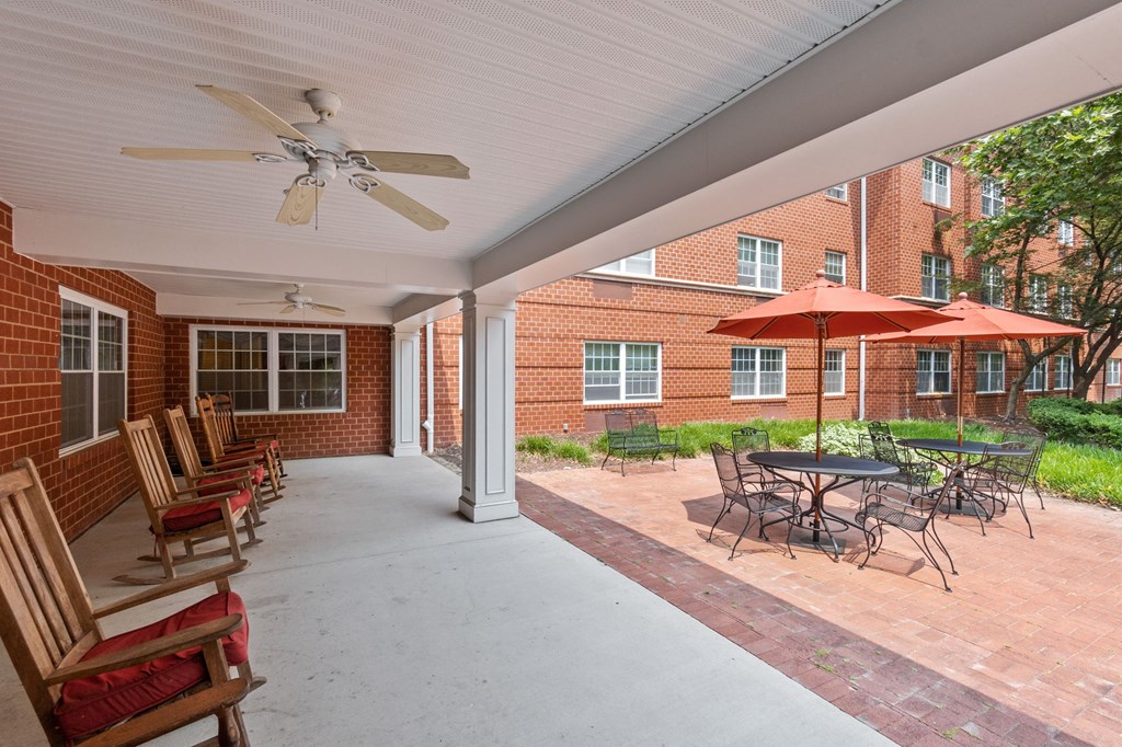 a covered patio with chairs and umbrellas in front of a brick building