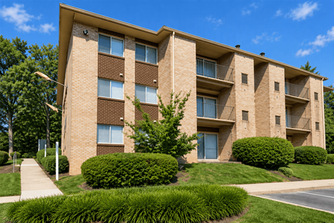 A multi-story apartment building with a well-manicured lawn in front.