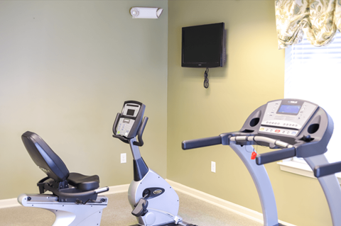 A gym with a treadmill and a stationary bike.