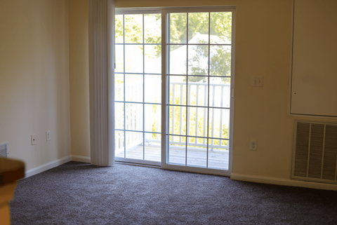 A room with a sliding glass door leading to a backyard.
