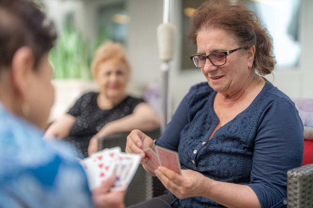 Seniors playing cards in a shared space at Greens at Irvington Mews II, 62+ apartments for active adults in Baltimore City.