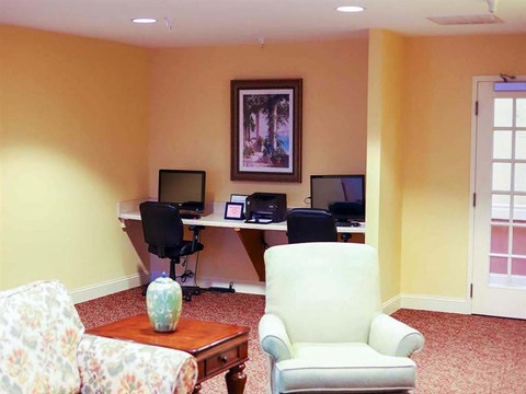 a living room with a desk with a computer and a chair