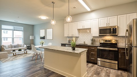 a kitchen and living room with white cabinets and stainless steel appliances