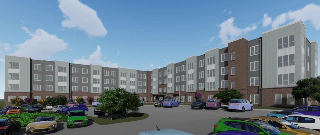 A parking lot with cars and a bus in front of apartment buildings.