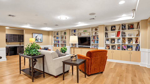 A living room with a fireplace, a couch, a chair, and a bookshelf filled with books.