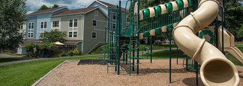 a playground with a slide and a building in the background