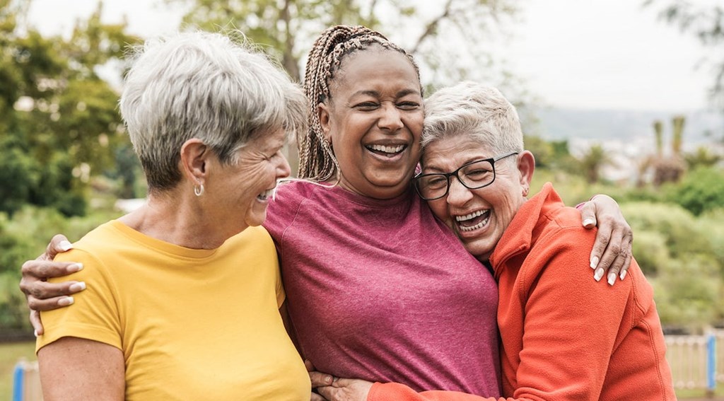 Seniors enjoying friendship and laughter outdoors near Greens at Irvington Mews II, a 62+ apartment community in West Baltimore, MD.