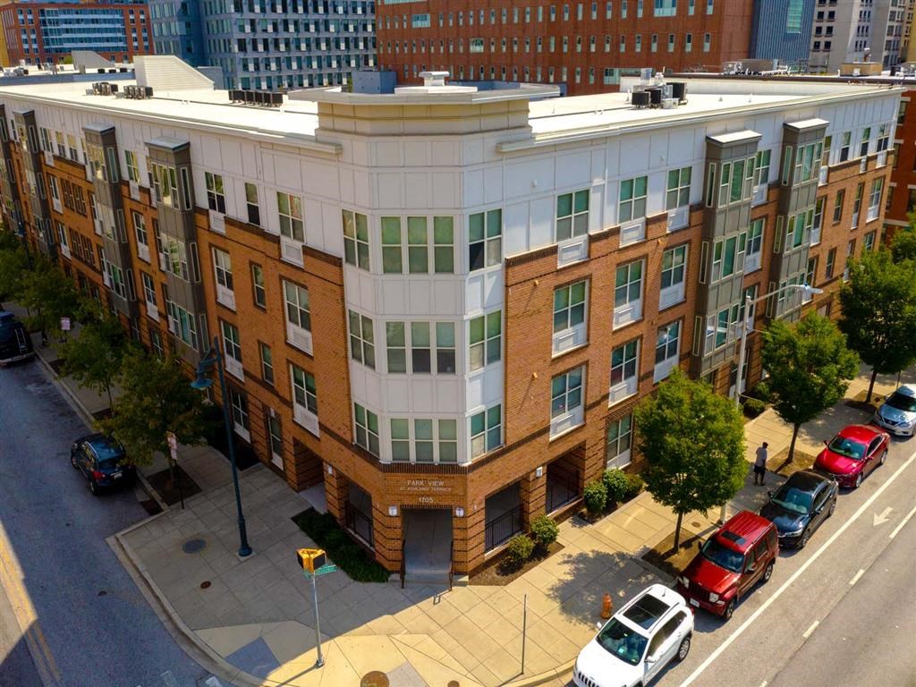 A street view of a multi-story building with cars parked in front.