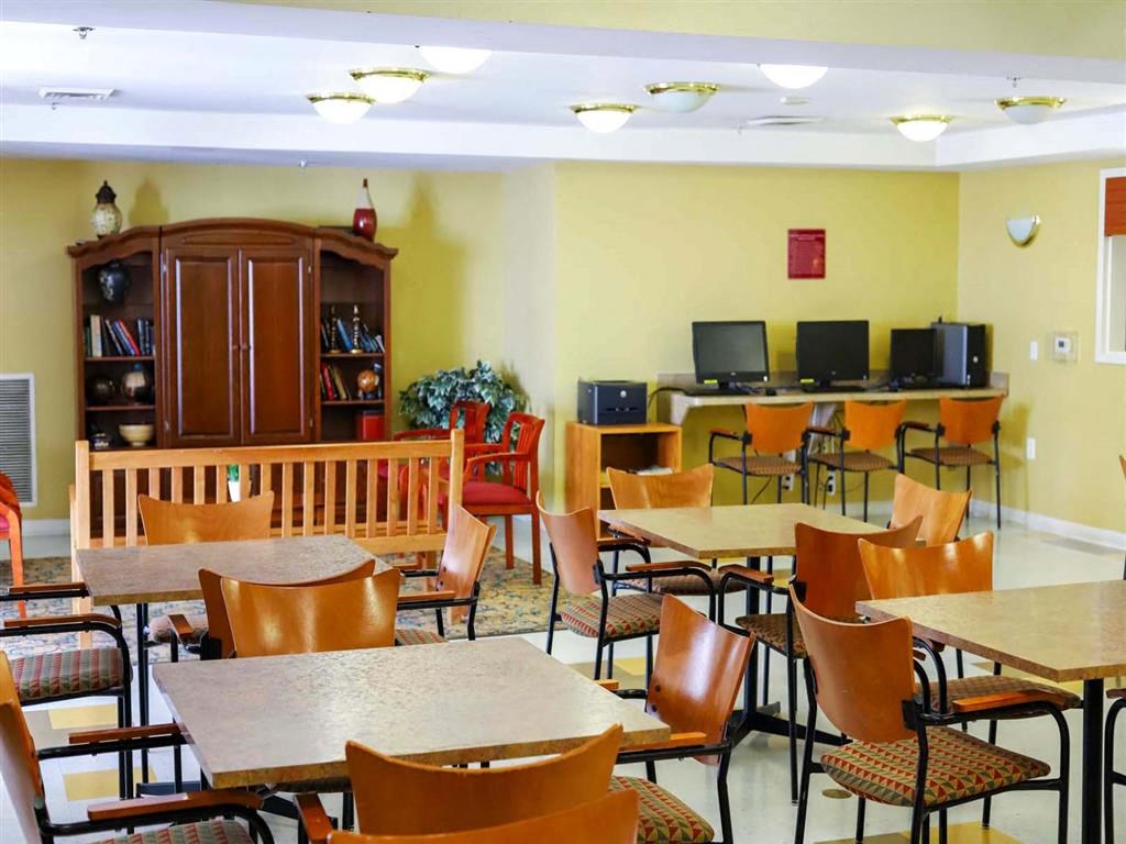 A room with tables and chairs and a bookcase.