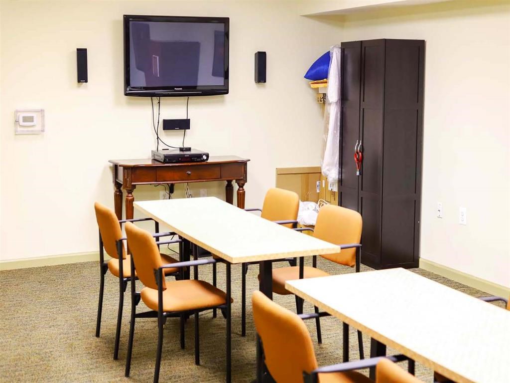 A conference room with a table, chairs, and a television.