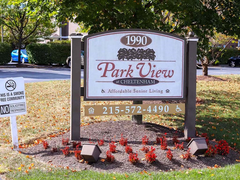 a park view sign with red flowers in front of a cemetery