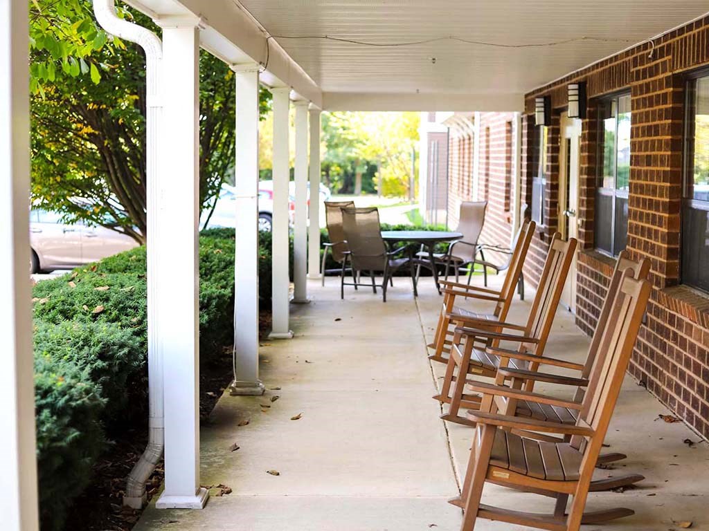 a row of wooden rocking chairs on a porch